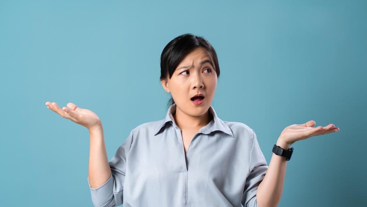 Asian woman angry annoyed and shrugging shoulders standing isolated over blue background&period;