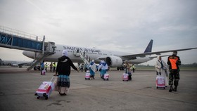 Jamaah calon haji kelompok terbang (kloter) pertama embarkasi Palembang (PLM 01) berjalan menuju pesawat yang akan membawa mereka menuju tanah suci, di Bandara Internasional Sultan Mahmud Baddarudin (SMB) II Palembang, Sumatera Selatan, Rabu (22/4/20