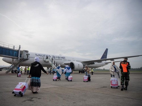 Jamaah calon haji kelompok terbang (kloter) pertama embarkasi Palembang (PLM 01) berjalan menuju pesawat yang akan membawa mereka menuju tanah suci, di Bandara Internasional Sultan Mahmud Baddarudin (SMB) II Palembang, Sumatera Selatan, Rabu (22/4/20