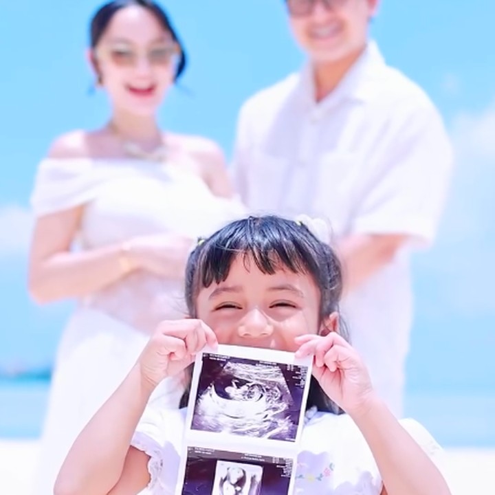 <p>Nanda bersama suami dan putri mereka kompak mengenakan baju bernuansa putih. Dalam satu momen, putri Nanda, Nadlyne Aurora, tampak memegang foto hasil USG sambil menunjukkan raut muka yang penuh kebahagiaan. (Foto: Instagram @nandaarsynt)</p>