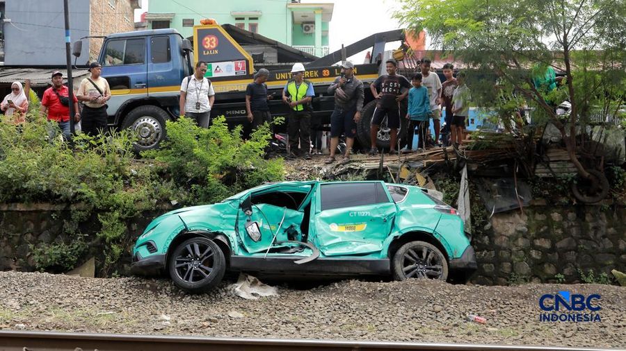 Kereta Krl melintas disamping taksi Green SM nan tertabrak KRL di perlintasan kereta Jalan Ampera, Bekasi, Selasa (28/4/2026). (CNBC Indonesia/Muhammad Sabki)