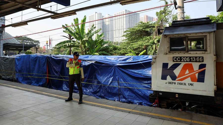 Seorang petugas keamanan berdiri di dekat puing-puing gerbong kereta komuter nan tertutup, tergeletak di letak setelah tabrakan fatal antara kereta komuter dan kereta jarak jauh pada hari Senin, di Bekasi, pinggiran Jakarta, Indonesia, 29 April 2026.