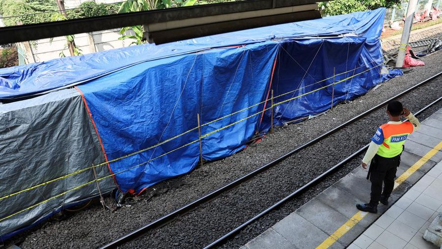 Seorang petugas keamanan berdiri di dekat puing-puing gerbong kereta komuter nan tertutup, tergeletak di letak setelah tabrakan fatal antara kereta komuter dan kereta jarak jauh pada hari Senin, di Bekasi, pinggiran Jakarta, Indonesia, 29 April 2026.