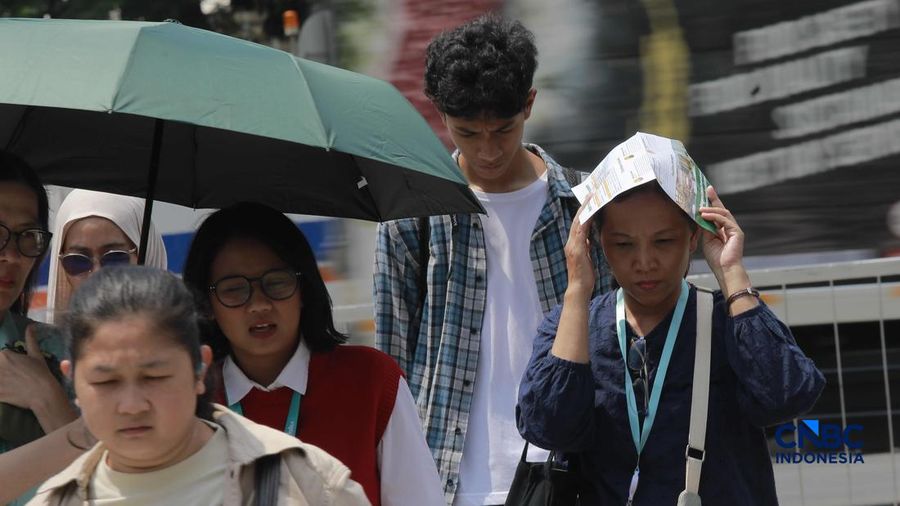 Warga melangkah dengan menutup kepala untuk berlindung dari terik mentari di Sudirman, Jakarta, Rabu (29/4/2026).