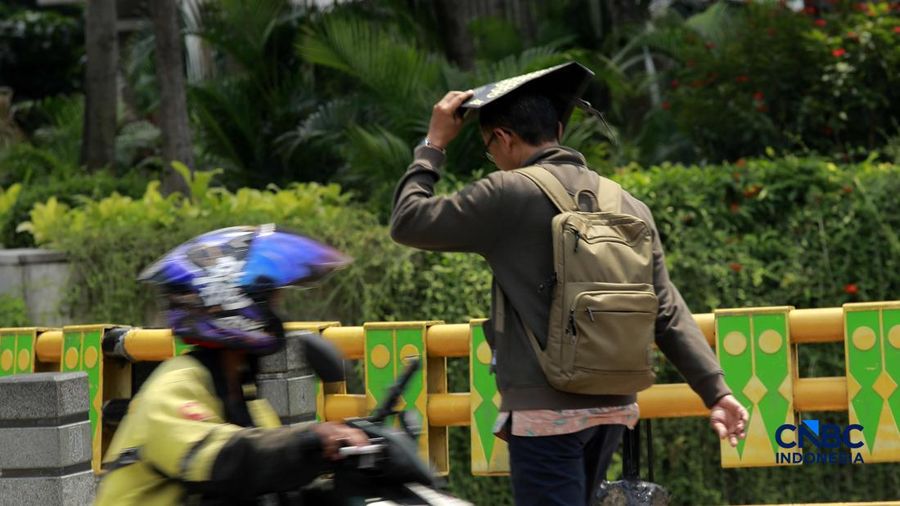 Warga melangkah dengan menutup kepala untuk berlindung dari terik mentari di Sudirman, Jakarta, Rabu (29/4/2026).