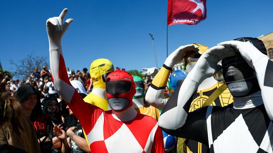 Orang-orang mengenakan kostum Power Rangers saat mereka berperan-serta dalam demonstrasi