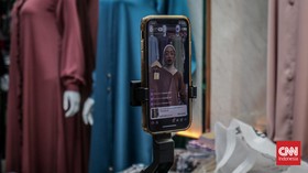 Seorang pedagang menjual taplak secara siaran langsung melalui aplikasi dagang elektronik di Pasar Tanah Abang, Jakarta Pusat, Kamis (7/5/2026). CNN Indonesia/Febria Adha L
