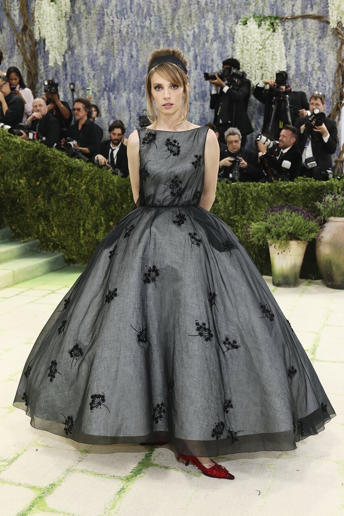 Feminin dan elegan, ball gown rancangan Prada yang membalut Maya Hawke menggabungkan bahan satin dengan lapisan luar organdi hitam yang dipercantik bordiran bunga senada. Outfit ini terinspirasi dari karya-karya pelukis abad ke-18 Jean-Honor&eacute; Fragonard. Hawke menyempurnakan gaya dengan perhiasan Prada Fine Jewelry Couleur/ Foto: Courtesy of Prada/Getty Images/Mike Coppola