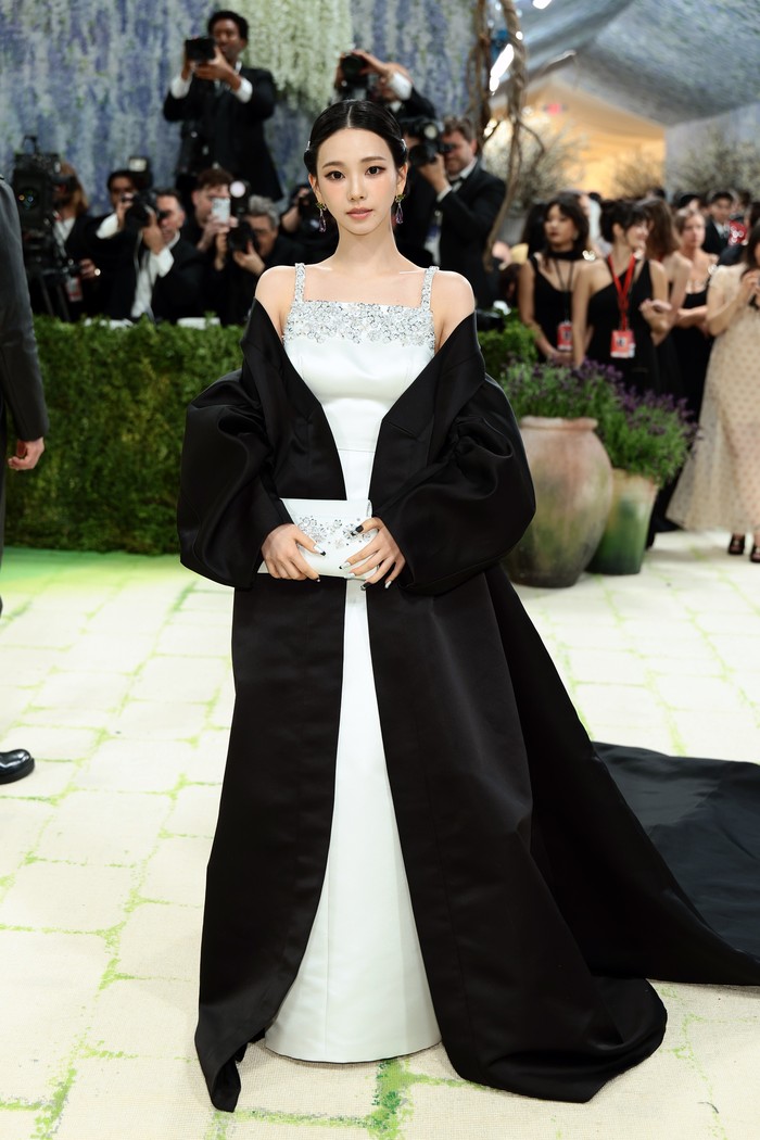 Mengutip dari Vogue Arabia, Prada mengambil beberapa inspirasi untuk merancang busana Karina aespa, termasuk desain neckline yang&nbsp;terinspirasi dari Hanbok Korea. Satin dress yang dikenakannya bertabur jet beads dan kristal perak, sedangkan cape hitam berbahan satin menambah kesan glamor pada gayanya/ Foto: Courtesy of Prada/Getty Images for The Met Museum//Dimitrios Kambouris