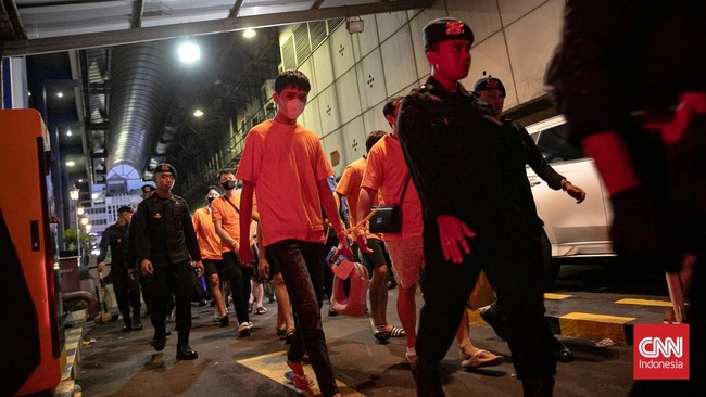 Ratusan terduga pelaku sindikat judi online jaringan internasional terlihat berjalan menuju bus untuk dipindahkan ke kantor imigrasi.