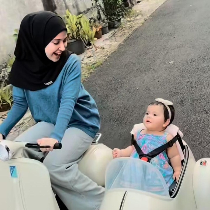 <p>Sepertinya Miskah memang gemar menyulap gaya <em>outfit</em> sang putri menjadi tampak modis. Dalam unggahan ini, Aisha mengenakan <em>dress</em> bermotif bunga yang berwarna biru. Sambil duduk di motor listrik yang dikendarai sang Bunda, Aisha tampaknya sangat menikmati momen tersebut, ya. (Foto: Instagram @miskashf)</p>