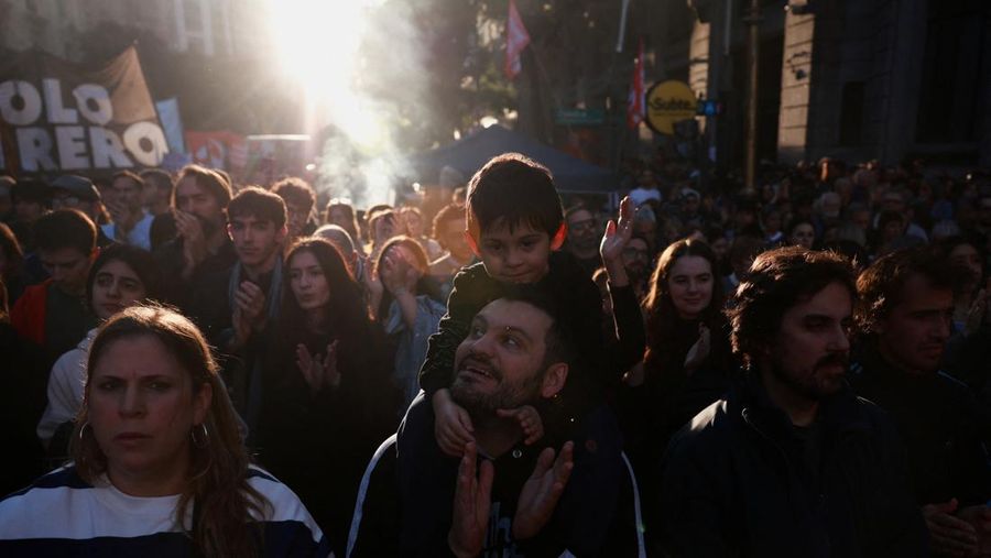 Seorang laki-laki menggendong seorang anak saat para pekerja dan mahasiswa universitas Argentina mengikuti pawai protes menentang pemotongan biaya universitas negeri, di Buenos Aires, Argentina, 12 Mei 2026.