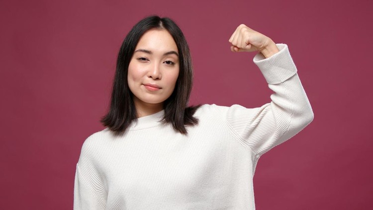 Young asian cheerful woman show flexed biceps against marsala copyspace