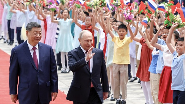 In this pool photograph distributed by the Russian state agency Sputnik, Russia's President Vladimir Putin (L) and China's President Xi Jinping take part in a welcome ceremony at the Great Hall of the People in Beijing on May 20, 2026. (Photo by Alex