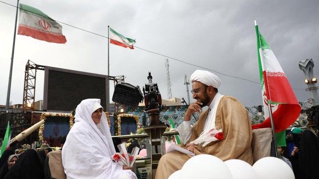 Peserta menjalani prosesi akad nikah di atas panggung yang dipimpin seorang ulama. (Majid Asgaripour/WANA via REUTERS)