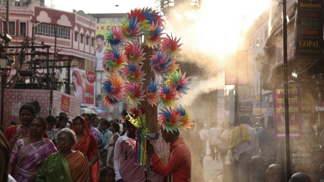 People walk under water sprinklers installed along a street on a hot summer day in Varanasi on May 15, 2026. (Photo by Niharika KULKARNI / AFP)