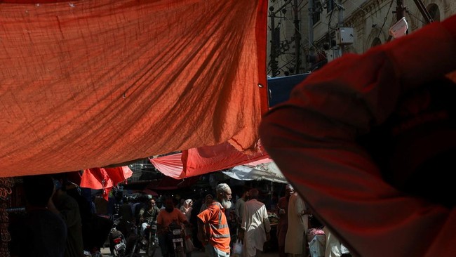 A person walks through a market, covered in sheets to block the hot summer sun in Karachi, Pakistan May 20, 2026. REUTERS/Akhtar Soomro