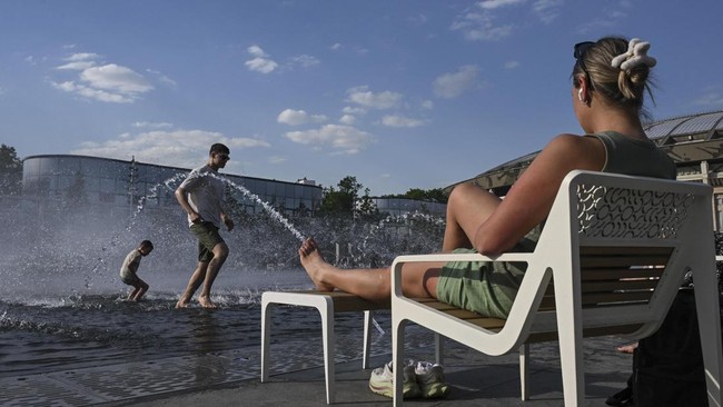 People cool off in a fountain next to the Luzhniki stadium during a hot day in Moscow on May 19, 2026. (Photo by Igor IVANKO / AFP)
