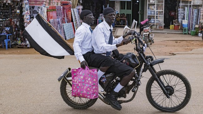 Supporters of a local football team ride on a motorcycle in Padea, on the border between Uganda and the Democratic Republic of Congo, on May 17, 2026. Ugandan officials confirmed that a 59-year-old man from DR Congo had died in Kampala after being ad