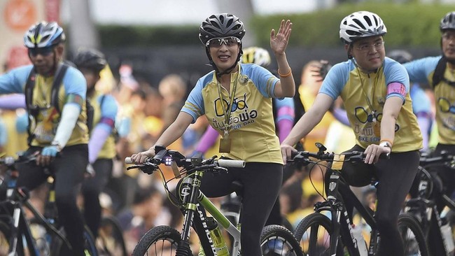 Thailand's Princess Bajrakitiyabha (C) waves as she rides a bicycle during a mass cycle event to honour King Bhumibol Adulyadej in Bangkok on December 11, 2015.  Thailand's crown prince Maha Vajiralongkorn led the symbolic 'Bike for Dad' event as par
