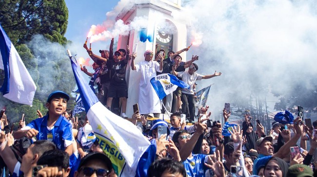 Suporter Persib dengan antusias menyambut arak-arakan dalam pesta juara Persib di Kota Bandung usai memastikan gelar juara Super League 2025/2026, Minggu (24/5) pagi. (ANTARA FOTO/Novrian Arbi)