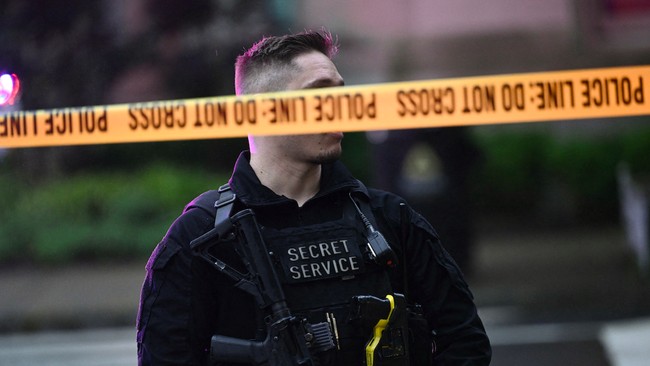 An armed secret service police officer stands behing tape blocking off a crime scene near the White House. Brendan SMIALOWSKI / AFP