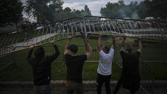 A group of demonstrators clash with riot police outside Serbia's parliament building during clashes that erupt at the end of an anti-government protest decrying corruption and calling for early elections following the collapse of a railway station ca