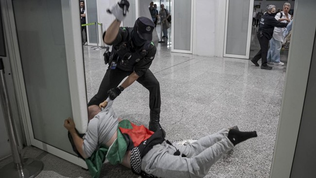 Basque police officers detain members of the Global Sumud Flotilla upon their arrival at Bilbao airport on May 23, 2026. Police detained four people at Bilbao airport in northern Spain on May 23, 2026 following clashes that broke out after activists