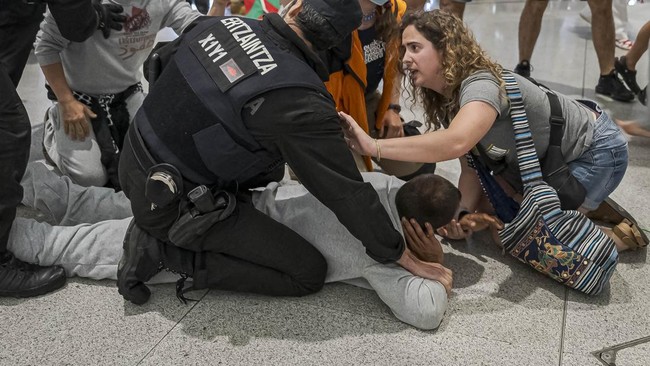 Basque police officers detain members of the Global Sumud Flotilla upon their arrival at Bilbao airport on May 23, 2026. Police detained four people at Bilbao airport in northern Spain on May 23, 2026 following clashes that broke out after activists