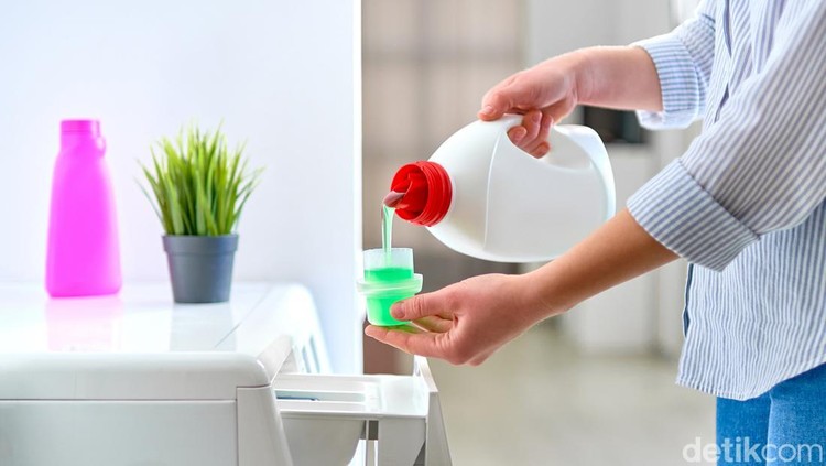 Woman housewife using fabric softener detergent gel for washing machine at laundry day