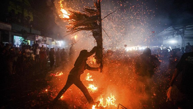 40 peserta membawa 400 obor menyala ke perempatan desa berpencar ke empat penjuru, lalu saling serang. (Photo by DEVI RAHMAN / AFP)