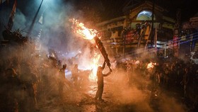 Para peserta melakukan Perang Obor yang terbuat dari daun kelapa kering yang menyala di Tegalsambi, Jawa Tengah, 25 Mei 2026. (DEVI RAHMAN / AFP)