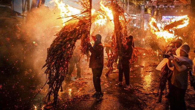 Puluhan peserta saling hajar menggunakan obor menyala dari pelepah kelapa kering berisi daun pisang dalam Perang Obor. (Photo by DEVI RAHMAN / AFP)