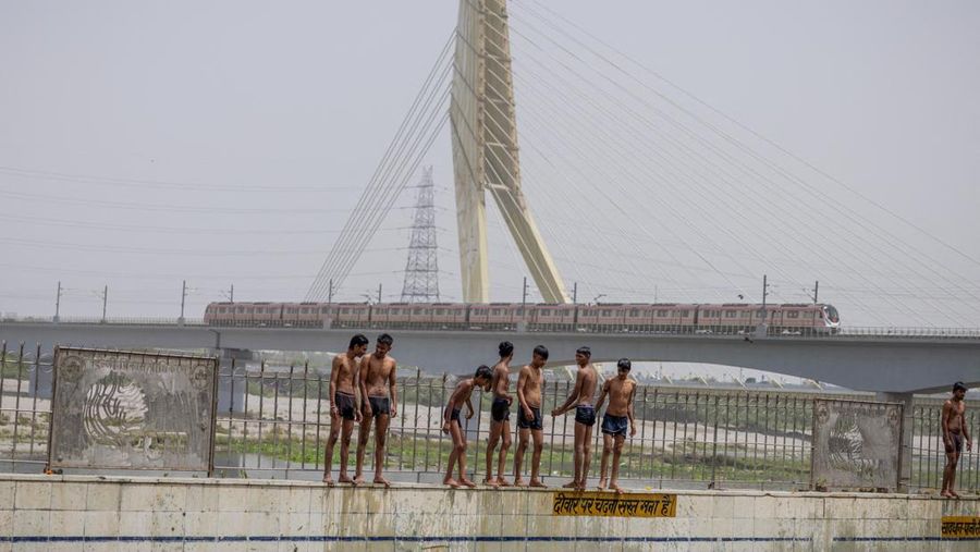Anak-anak laki-laki bersiap untuk melompat di kolam renang umum pada hari musim panas nan terik di New Delhi, India, 25 Mei 2026.