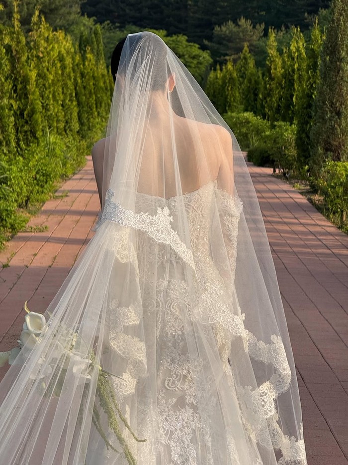 Bahkan tampilan belakang Yoon Ha Jeong dalam balutan gaun pernikahan juga cantik, Beauties. Kain veil menggandakan volume mewah yang terdapat pada gaun putih pelambang sucinya sebuah perasaan./ Foto: instagram.com/hi_jjeong2