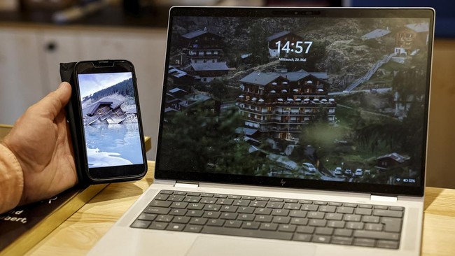 Lukas Kalbermatten shows a picture of his destroyed Edelweiss hotel, next to a screensaver picture of the same Hotel, nearly a year after a massive rock and ice slide triggered by the collapse of the Birch Glacier destroyed much of the village of Bla