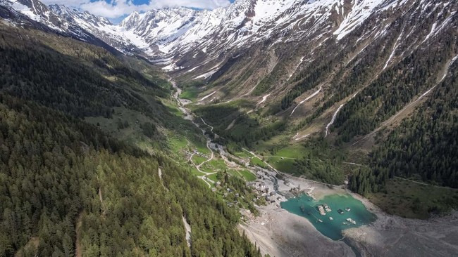 A drone view shows a few remaining houses surrounded by the Lonza River nearly a year after a massive rock and ice slide triggered by the collapse of the Birch Glacier destroyed much of the village of Blatten, Switzerland, May 13, 2026. REUTERS/Denis