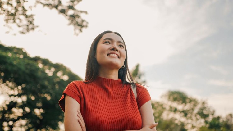 Smiling woman enjoying nature and freedom in sunny park setting