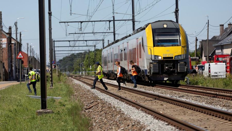 Petugas darurat melangkah di dekat letak kejadian di mana sebuah bus sekolah ditabrak kereta api di perlintasan sebidang nan menyebabkan banyak korban jiwa, dekat kota Buggenhout, Belgia, 26 Mei 2026.