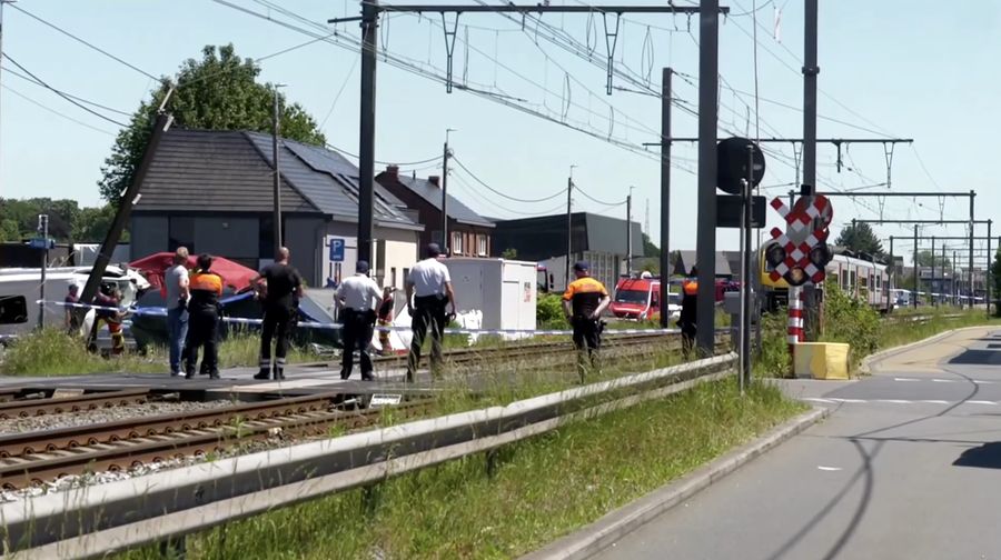 Tim penyelamat memandang bus sekolah nan rusak usai tertabrak kereta di sebuah perlintasan rel di wilayah Flanders utara, Beglia Selasa (26/5/2026) pagi waktu setempat. (Tangkapan Layar Video Reuters/)