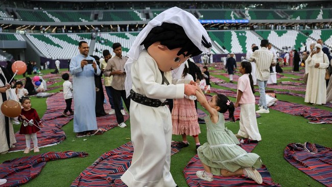 A person in a costume plays with a girl while entertaining children after Eid al-Adha prayers at Education City Stadium in Al Rayyan, Qatar, May 27, 2026. REUTERS/Saleh Salem