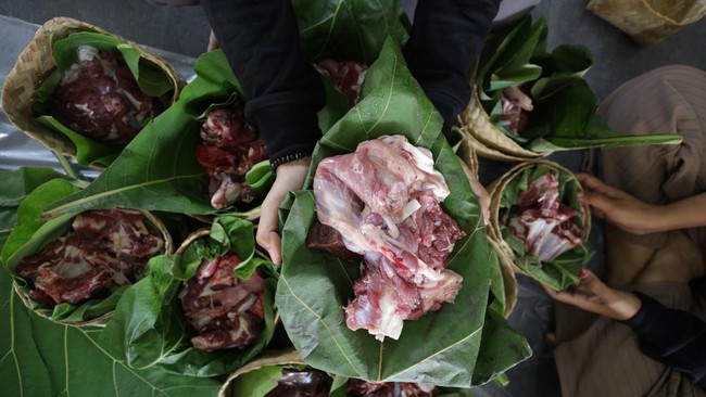 Warga memperlihatkan daging kurban yang dikemas menggunakan besek bambu beralaskan daun jati di Masjid Al-Khalid Kota Kediri, Jawa Timur, Rabu (27/5/2026). Pemanfaatan besek dan daun jati sebagai pembungkus daging kurban tersebut sebagai upaya menduk
