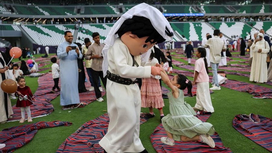 Seseorang nan mengenakan kostum bermain dengan seorang gadis sembari menghibur anak-anak setelah salat Iduladha di Stadion Education City di Al Rayyan, Qatar, Rau (27/5/2026). (REUTERS/Saleh Salem)