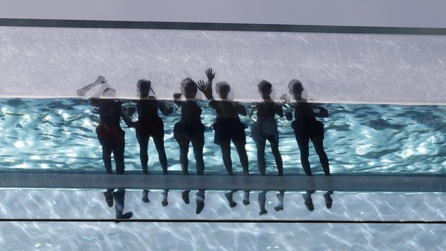 Swimmers relax in the Sky Pool - a transparent acrylic swimming pool bridge fixed between two apartment blocks - at Embassy Gardens in south-west London on May 24, 2026, as temperatures increase to heatwave levels and are set to rise further over the