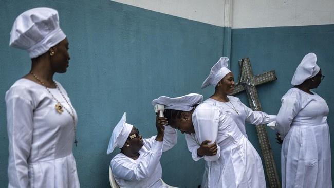 A worshipper uses a fan on another head inside the compound of the Celestial Church of Christ International Headquarters in the Ketu neighbourhood in Lagos on May 24, 2026. (Photo by OLYMPIA DE MAISMONT / AFP)