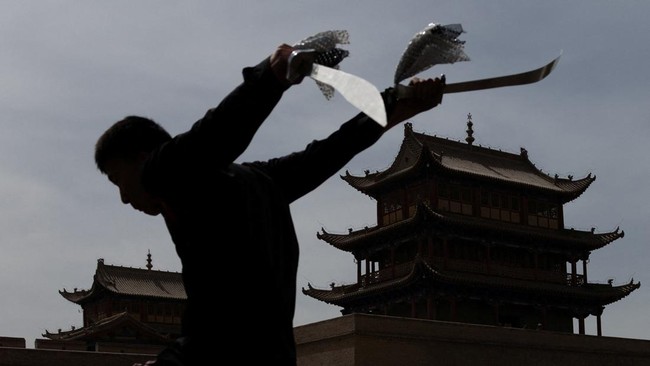 A performer practices martial arts with swords at Jiayu Pass, a strategic point along the Great Wall and the ancient 'Silk Road', in Jiayuguan, Gansu province, China, May 22, 2026. REUTERS/Maxim Shemetov