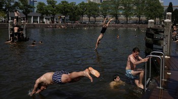 People swim during an unseasonably hot day at the Marineterrein in Amsterdam, Netherlands, May 26, 2026. REUTERS/Stelios Misinas