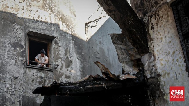 Sejumlah warga mengevakuasi barang dari rumah yang hangus terbakar di Krendang, Jakarta Barat, Jumat (29/5/2026). (CNN Indonesia/Febria Adha L)