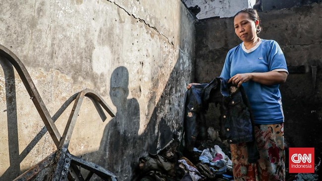Sejumlah warga mengevakuasi barang dari rumah yang hangus terbakar di Krendang, Jakarta Barat, Jumat (29/5/2026). (CNN Indonesia/Febria Adha L)