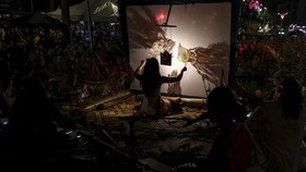 Master puppeteer Illya Sumanto of the all-female Wayang Women troupe moves the puppets between the light bulb and screen to create shadows during the Wayang Kulit or traditional shadow puppet show, a tradition long led predominantly by men, in Kuala